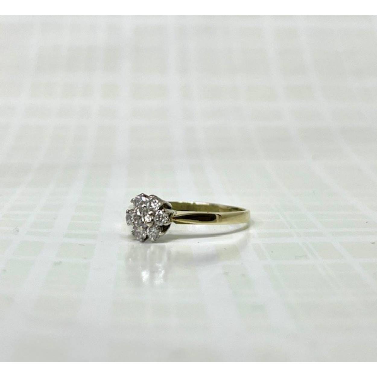 Deze prachtige gouden vintagering heeft een schitterende entourage zetting van 7 briljant geslepen diamanten. De scheen is 1.9 mm breed en de kop van de ring is 6.8mm.

