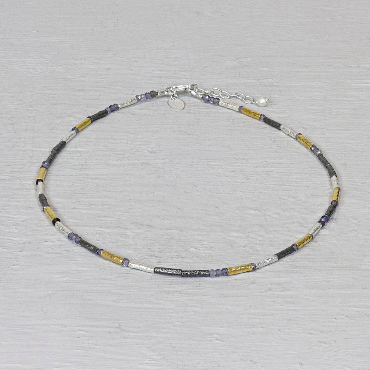 Dit collier is gemaakt van buisjes van verschillende materialen. Er is zowel zilver, geoxideerd zilver, goldfilled en Ioliet gebruikt. Dit maakt deze ketting zo makkelijk te combineren met elke outfit. 