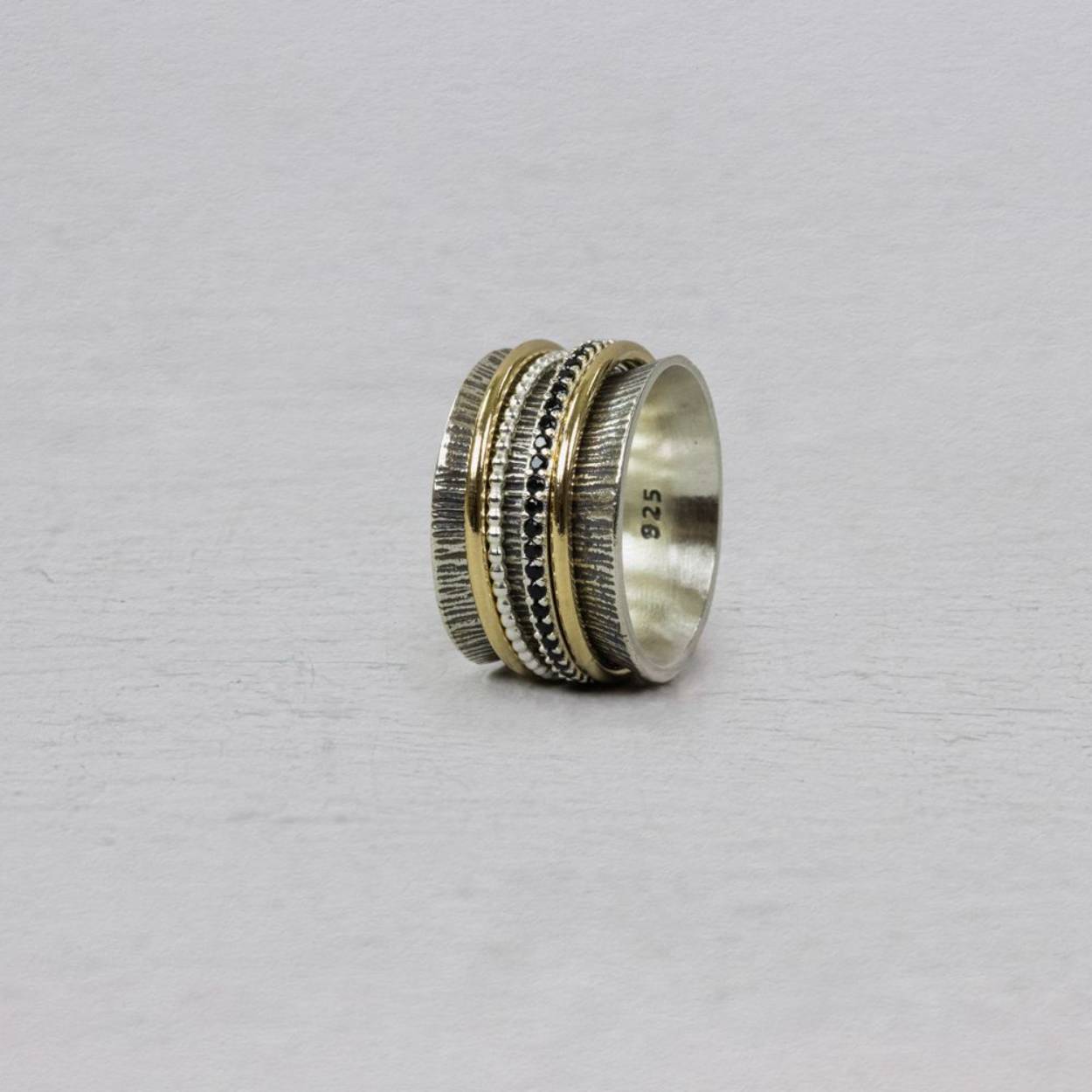 Ring gemaakt van 925 sterling zilver, met daaromheen ringen van Goldfilled, geoxideerd zilver en zirkonia's. Deze ring met een breedte van 1,5 cm loopt rond aan de binnenkant waardoor hij heel lekker zit. 

Maat 57 en verkrijgbaar in diverse maten.