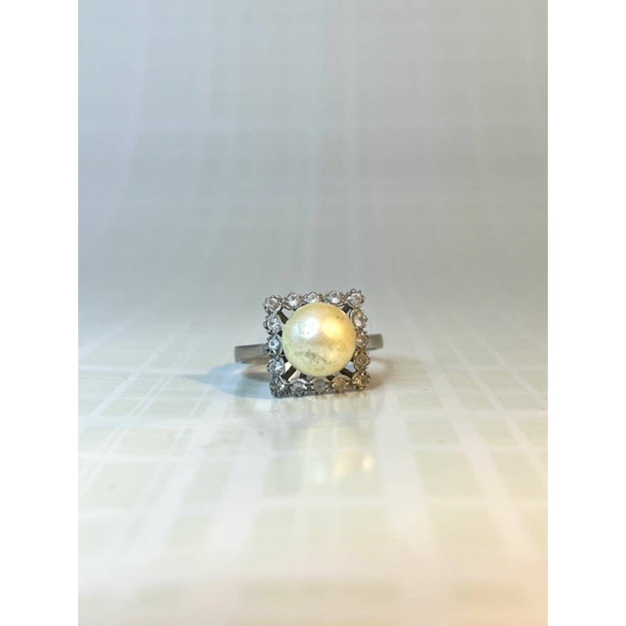 Deze prachtige vintagering is gemaakt van witgoud met een legering van 18 karaat. De ring heeft een parel met daaromheen zirkonia. 