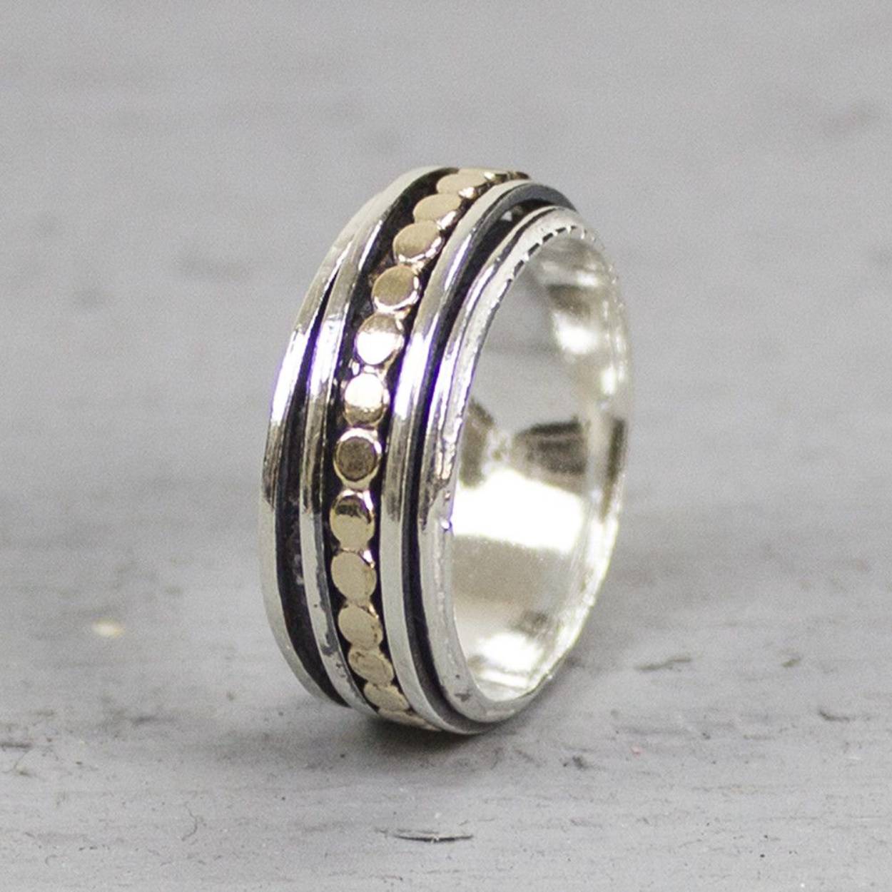 Deze ring is gemaakt van 925 sterling zilver en gold filled. De ring heeft drie losse ringetjes die afzonderlijk van elkaar kunnen bewegen. De ringetjes bestaan uit twee zilveren en één gold filled ringetje in de vorm van platte balletjes. De onderkant van de ring is geoxideerd wat zorgt voor extra diepte.