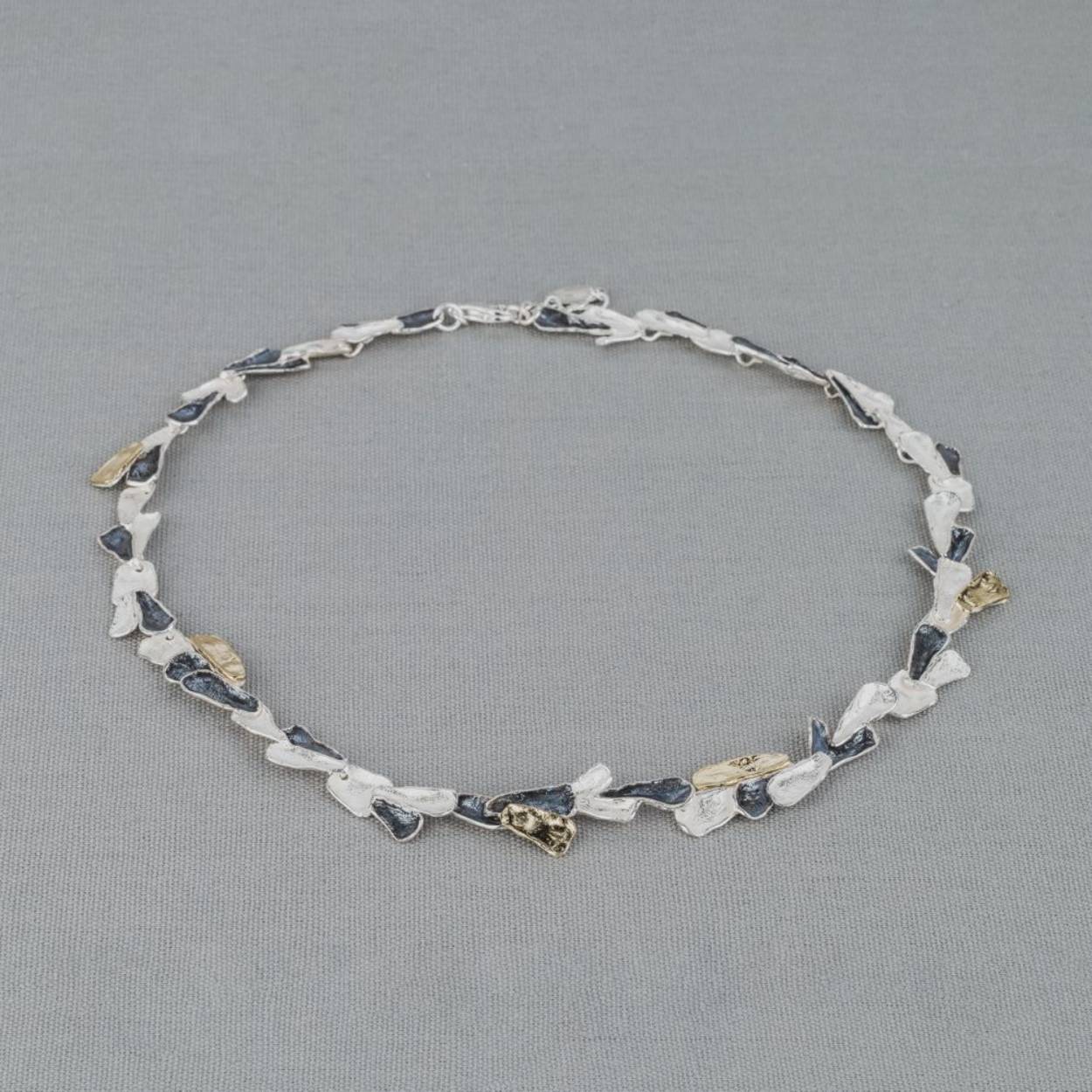 Collier gemaakt van 925 (geoxideerd) sterling zilver en zilver verguld. Dit schakelcollier is door de drie kleuren en verschillende organische schaaltjes een echt Jéh collier. Combineer met een mooie armband en oorbellen voor een complete look!