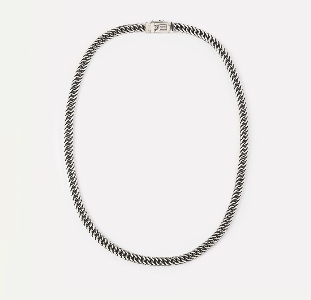 Ervaar de stoere Esther Short Ketting, gemaakt met het iconische Esther-ontwerp. Handgemaakt met nauwgezet vakmanschap, is elke schakel verweven om een gedurfde en verfijnde look te creëren. De donkere elementen in het 925 zilver, verkregen door oxidatie, geven de Esther-collectie haar kenmerkende Buddha to Buddha touch. Dit veelzijdige sieraad is een modieuze ketting voor vrouwen of een opvallende choker voor mannen. Omarm je unieke stijl met deze bijzondere ketting, ontworpen om individualiteit te uit te stralen en een gedurfd statement te maken. 